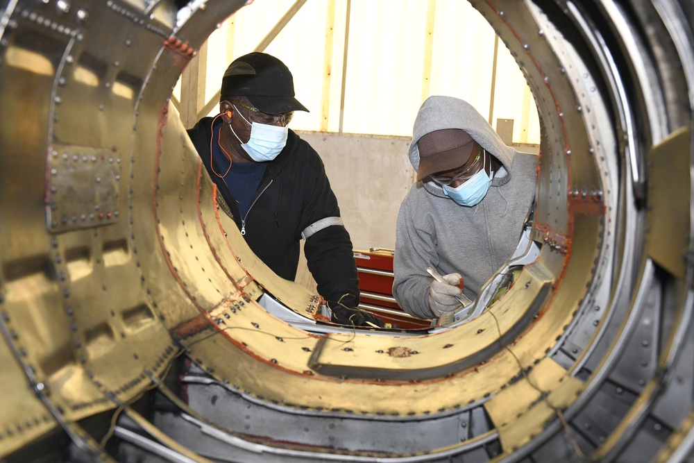 FRCSE mechanics install fire shields on the boat tail of an F-5 Tiger II