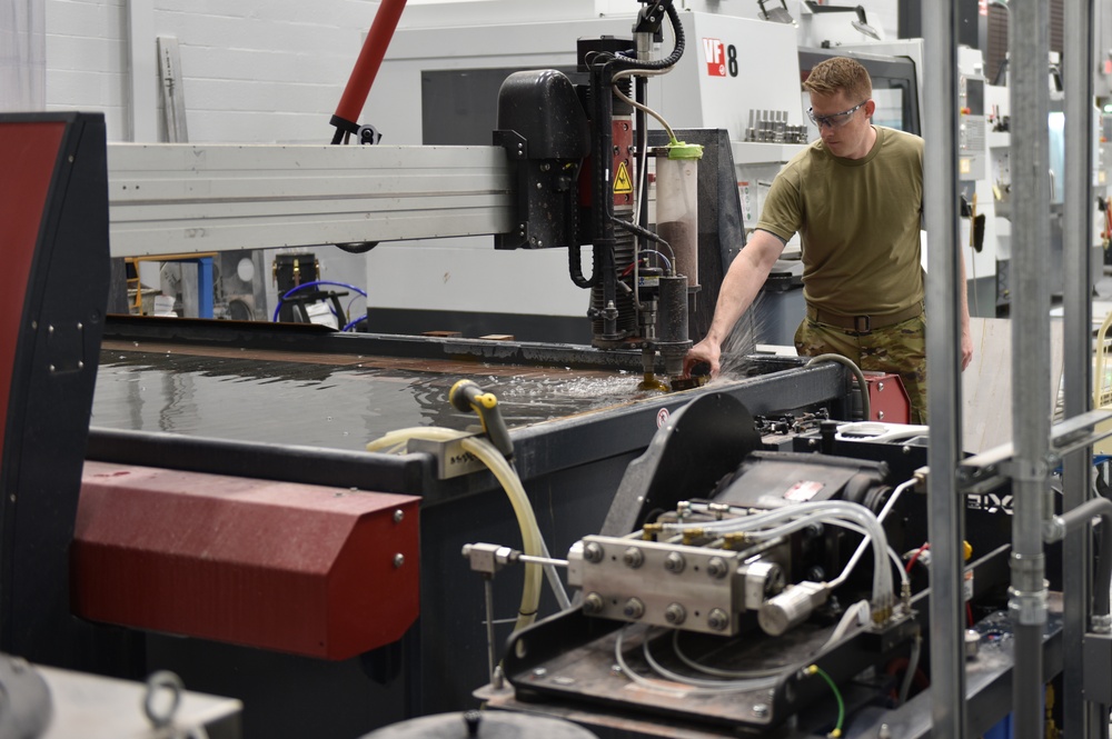Splish, splash I was… positioning a metal block on the water jet cutting table