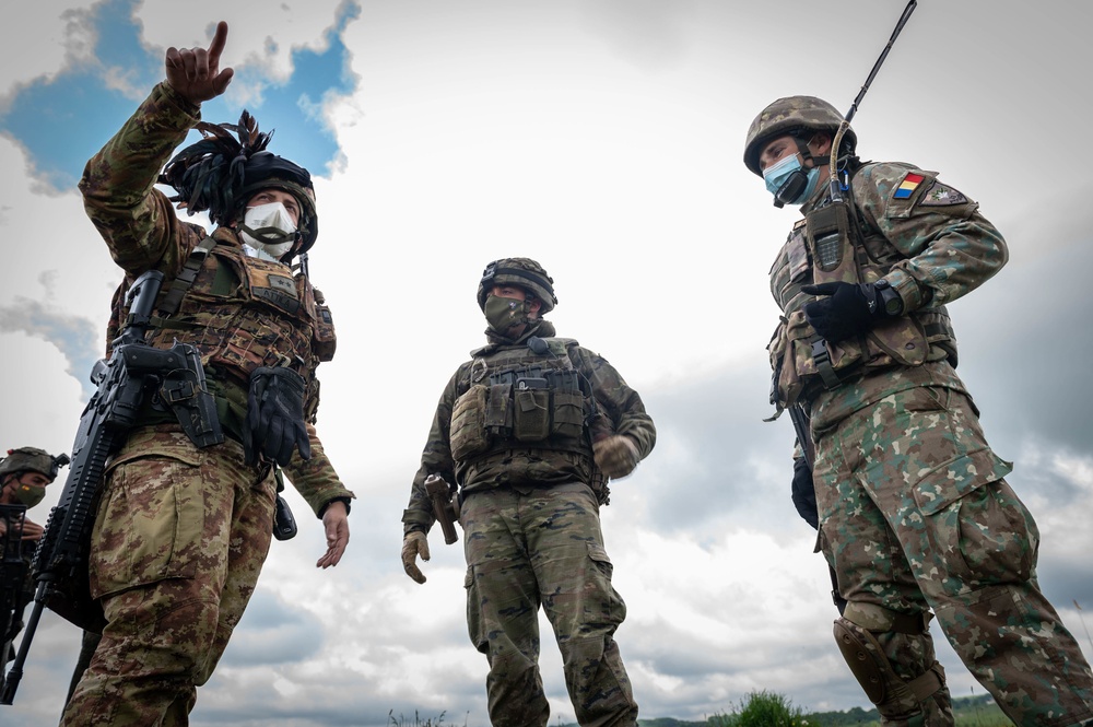 Italian, Spanish and Romanian Soldiers discuss tactics while conducting reconnaissance training during Exercise Steadfast Defender 2021 in Romania.