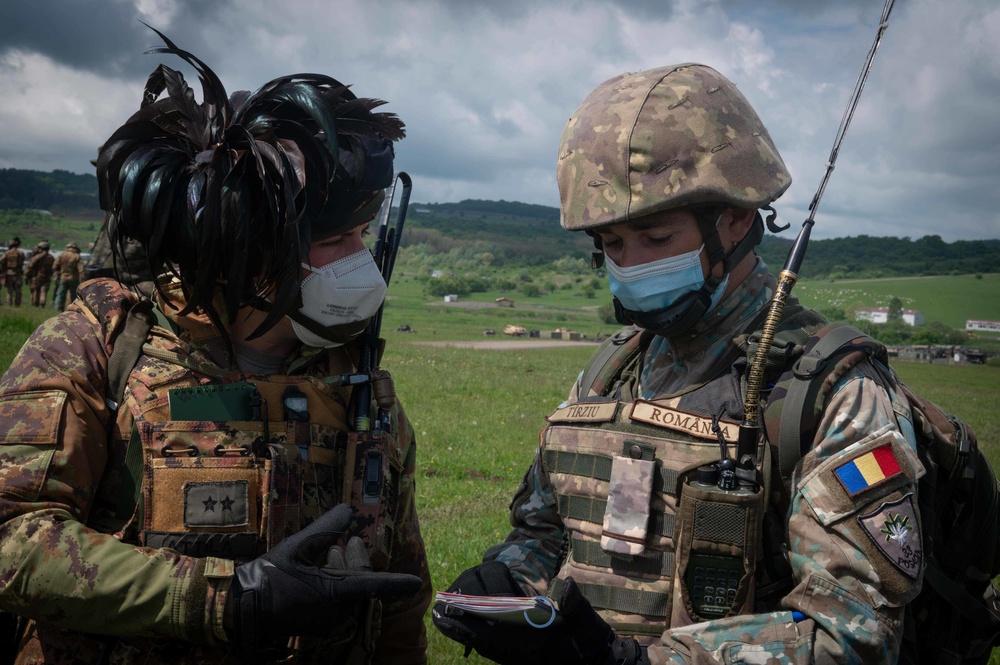 Italian and Romanian Soldiers discuss tactics while conducting reconnaissance training during Exercise Steadfast Defender 2021 in Romania