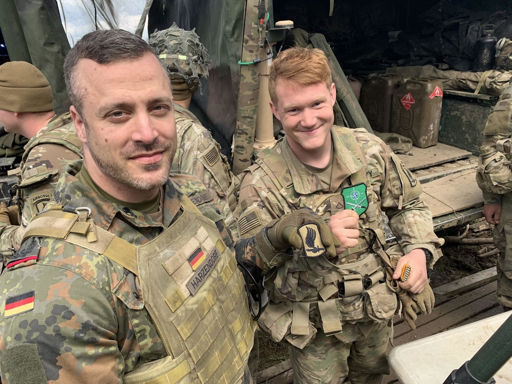 International Relations: German Officer and U.S. Soldier Exchange Patches at the Gun Line