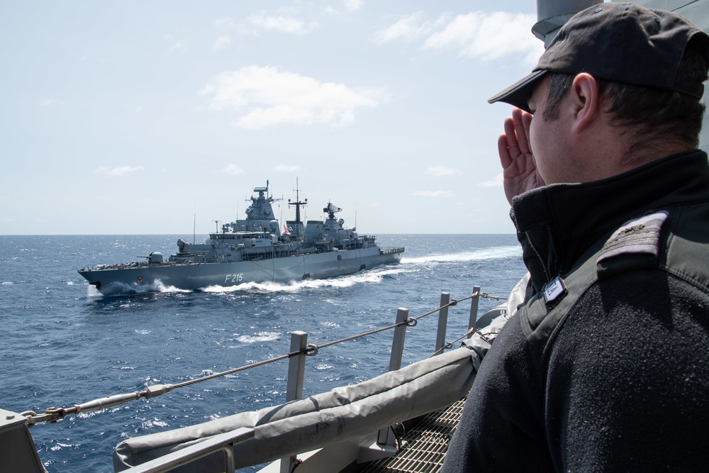 A NATO Soldier salutes while FGS Brandenburg (F215) sailing past Standing Nato Maritime Group 2 (SNMG2) Flagship ESPS Mendez Nunez  prior to her departure from NATO Steadfast Defender 2021.