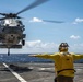 A Military Sealift Command civil service mariner guides an MH-60 Sea Hawk helicopter