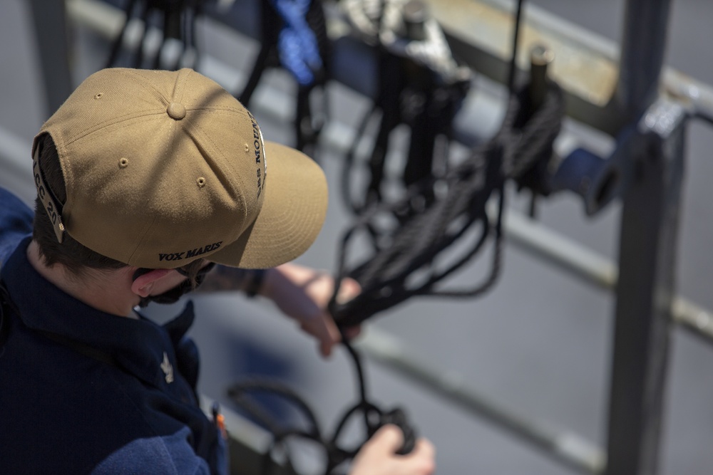 Operations Specialist 3rd Stephanie Tessier handles rigging line as the Blue Ridge-class command and control ship USS Mount Whitney (LCC 20) gets underway from Rota, Spain during Exercise Steadfast Defender 2021