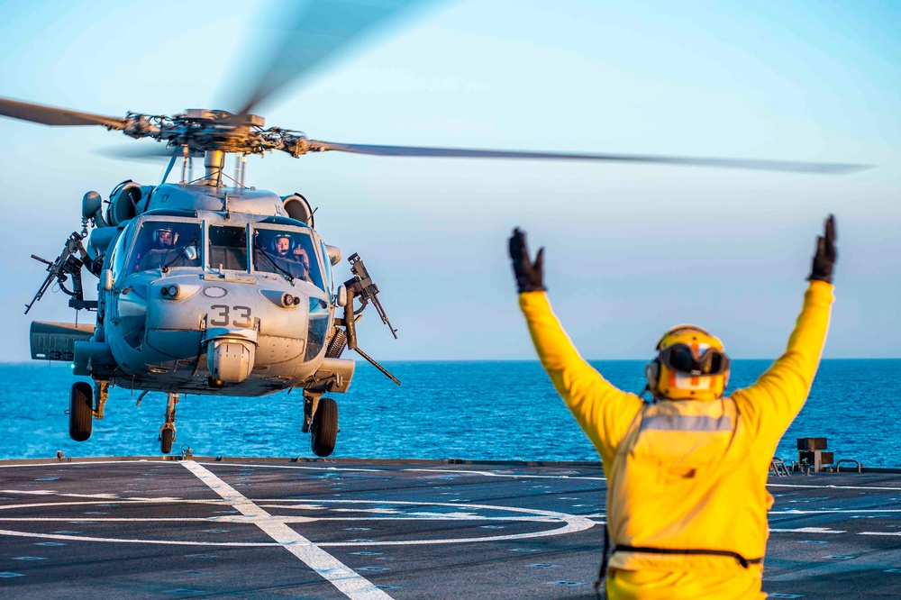 A Military Sealift Command civil service mariner launches an MH-60 Sea Hawk helicopter