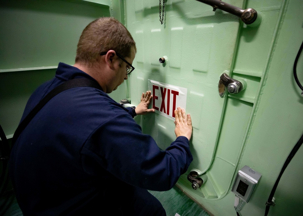 USS Sioux City Sailor Replaces Sign on Hatch