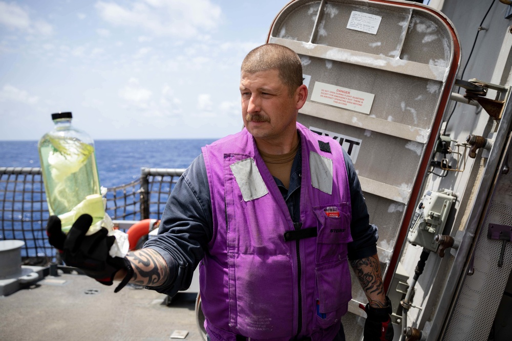 USS Sioux City Sailor Inspects a Fuel Sample on the Flight Deck