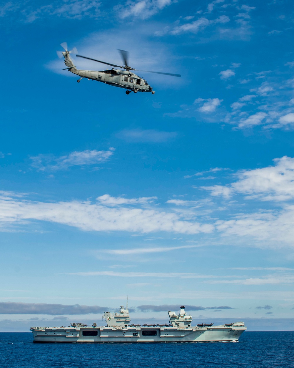 An MH-60 Sea Hawk helicopter  flies towards the HMS Queen Elizabeth during Exercise Steadfast Defender 2021