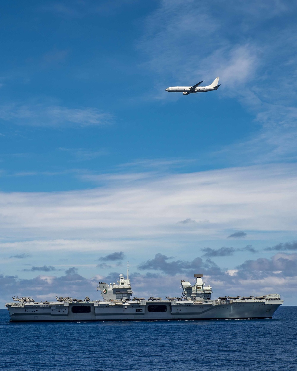 A P-8A Poseidon maritime patrol aircraft flies over the HMS Queen Elizabeth during Steadfast Defender 2021