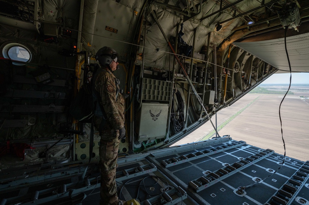 Loadmaster looks out the back end of a C-130 Hercules