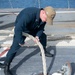 Sonar Technician Surface 3rd Class Nicolas Kane, from Byron, Ill., passes a mooring line through a hatch