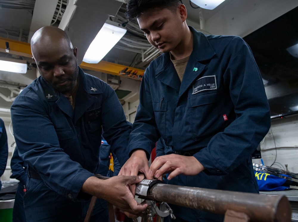 Damage Controlman 1st Class Jacob Lighten (left), from St. Louis, Mo., demonstrates how to apply a jubilee patch with Gas Turbine Systems Technician Fireman Emerico Veluz (right), from Reading, Pa.