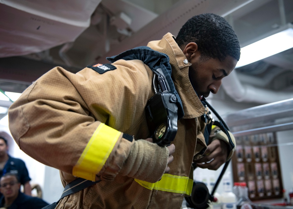 Operations Specialist Seaman Shemar Dyett, from Waytross, Ga., dons a self-contained breathing apparatus during a firefighting drill