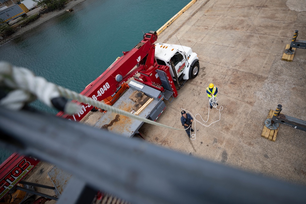 USS Sioux City Sailor Steadies Crane Basket on Ship's Mast While in Port