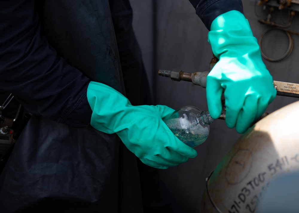 USS Sioux City Sailor Collects a Fuel Sample During a Refueling