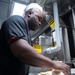 Culinary Specialist 3rd Class Marcus Davis kneads dough for bread in the galley