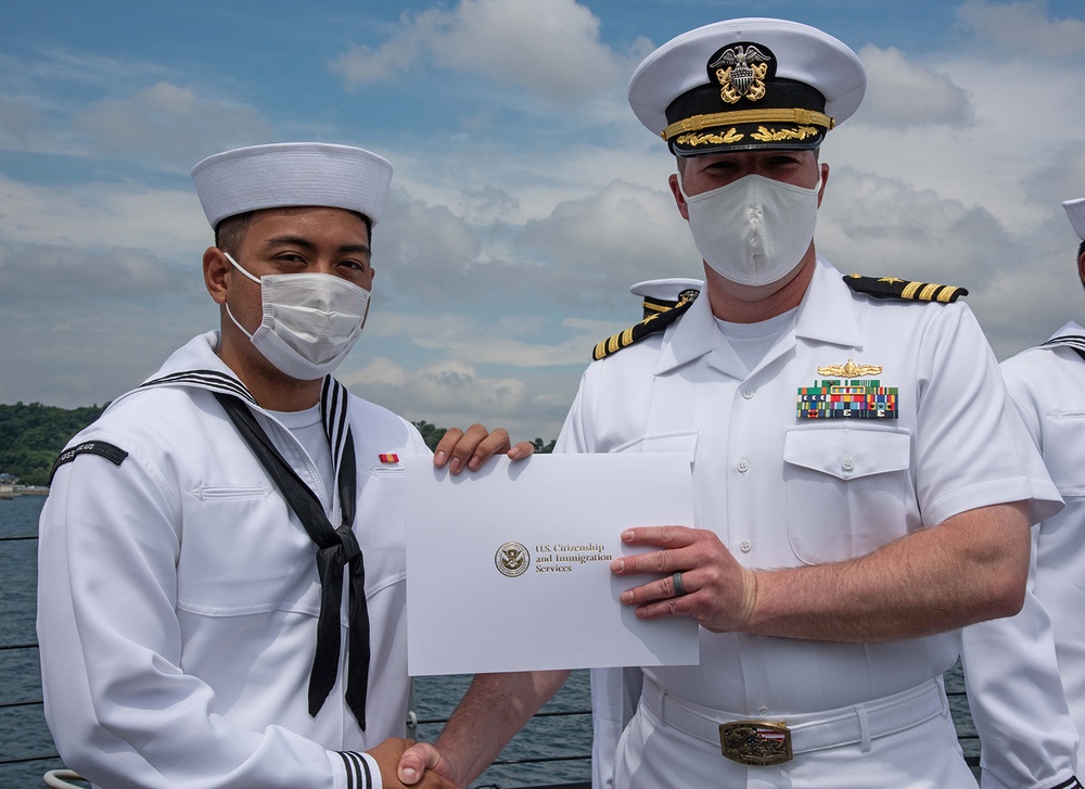 Two Sailors and one Soldier become new citizens of the U.S. during a naturalization ceremony aboard USS Milius stationed at CFAY