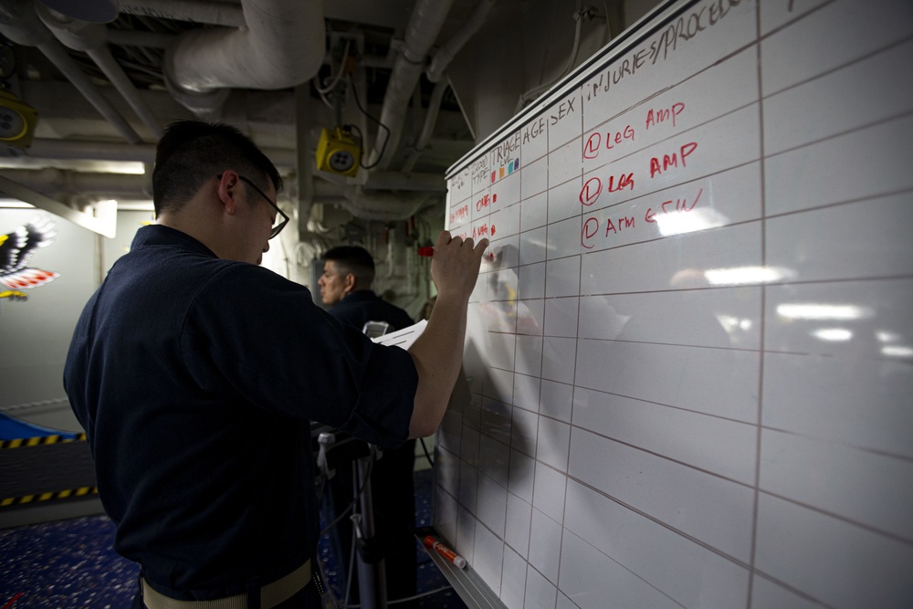 US Navy Sailors conduct a simulated mass casualty drill in response to a helicopter raid training exercise