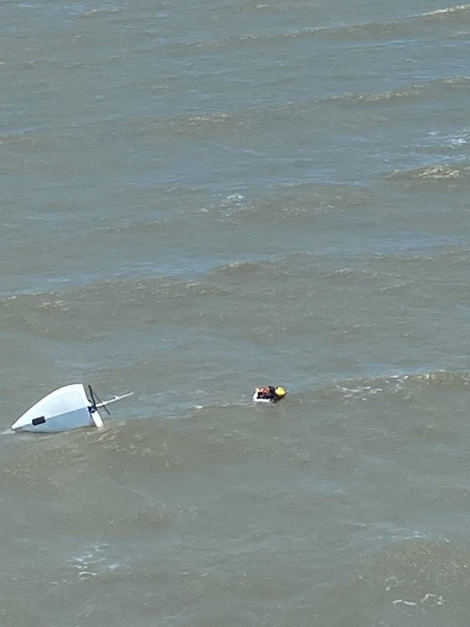 U.S. Coast Guard aircrew rescue man from capsized sailing vessel