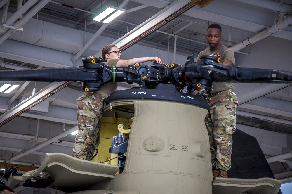 Soldiers conduct maintenance on the forward rotor of a CH-47 Chinook helicopter.