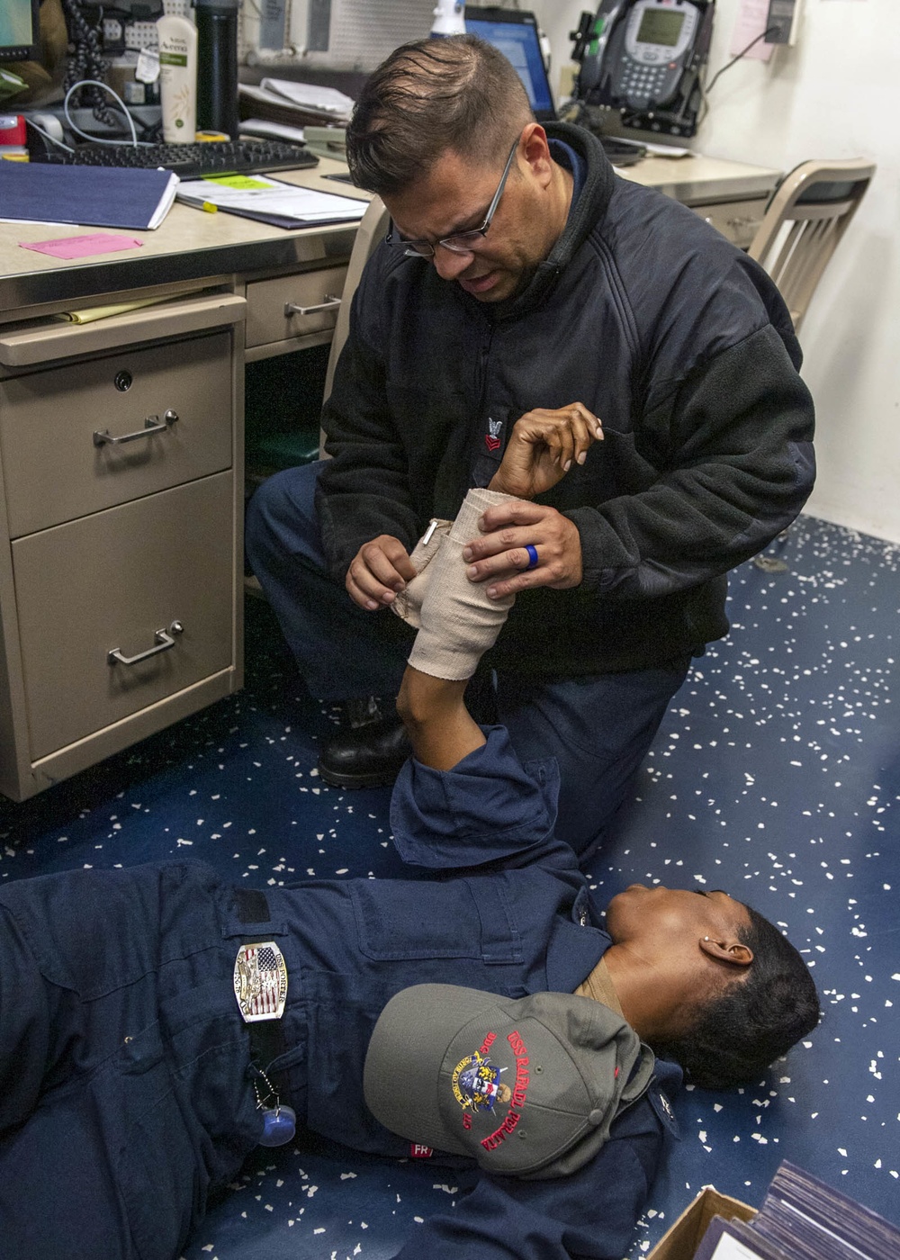 Yeoman 1st Class Luis Ramos-Perez (top), from Wichita, Kan., conducts first-aid training with Hospital Corpsman 2nd Class Adia Corbin (bottom), from Dallas, Texas