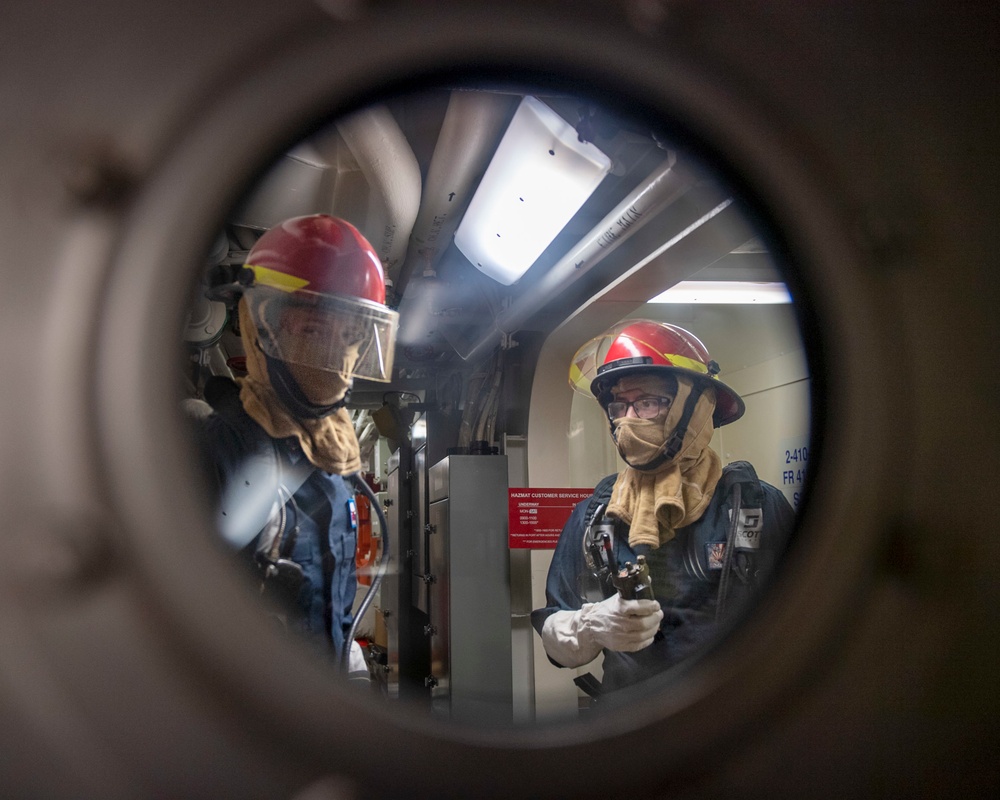 Sailors investigate for a simulated fire during a fire fighting drill