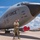 A U.S. Air Force service member in OCP (Operational Camouflage Pattern) uniform stands with arms crossed in front of a large military aircraft on a flight line. The aircraft is marked 'U.S. AIR FORCE' and displays unit designations including 6 ARW and 927 ARW, consistent with a KC-135 Stratotanker. The photo appears to be a formal or commemorative portrait taken on a sunny day at what appears to be MacDill Air Force Base, Florida.