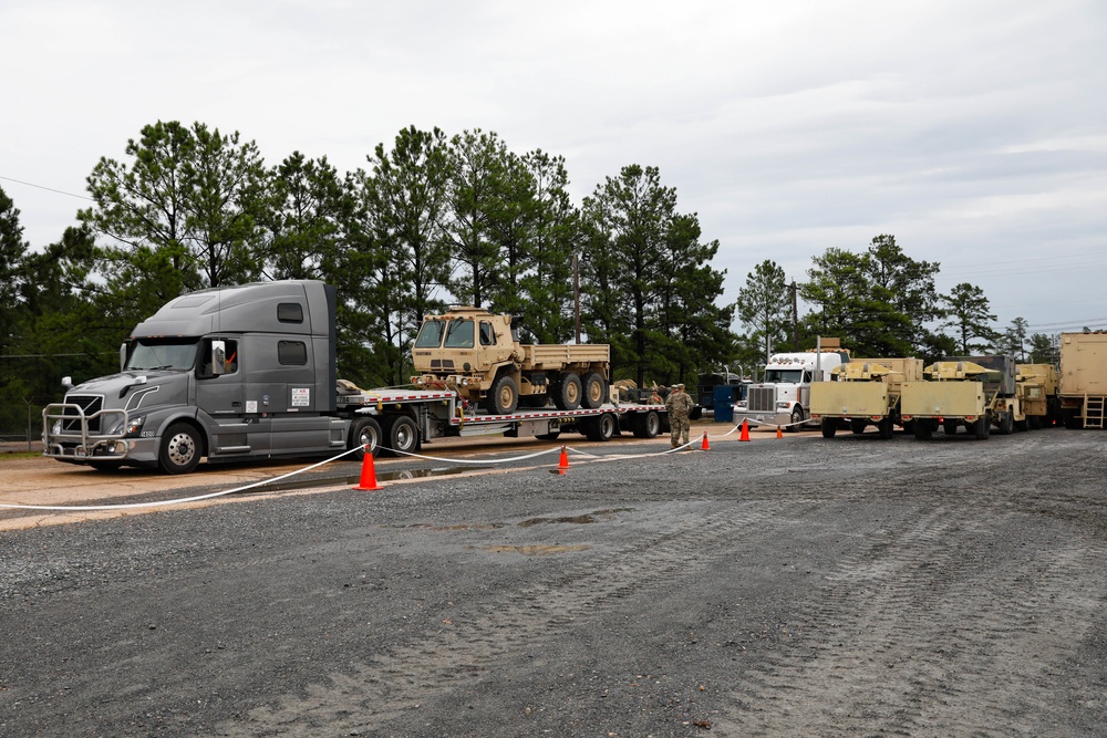 Soldiers and civilians work together to transport military vehicles