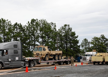 Soldiers and civilians work together to transport military vehicles
