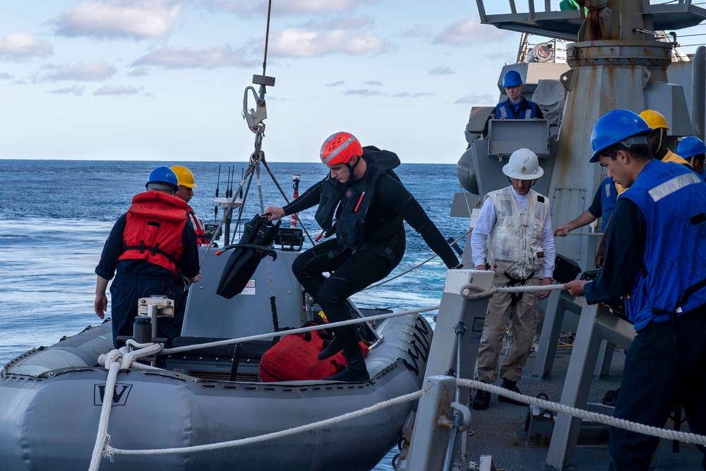 Sailors embark a ridged-hull inflatable boat (RHIB)