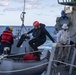 Sailors embark a ridged-hull inflatable boat (RHIB)