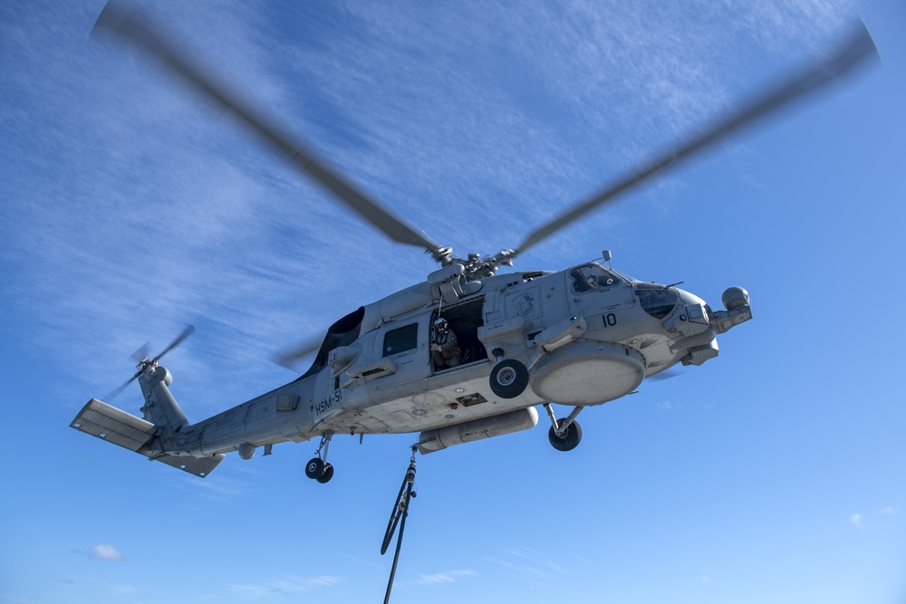 An MH-60R Seahawk assigned to the “Warlords” of Helicopter Maritime Strike Squadron (HSM-51) prepares to conduct a helo in-flight refueling (HIFI)