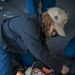 Culinary Specialist 3rd Class Shayla Collins, from New Orleans, La., secures Aviation Electronics Mate 2nd Class Bethany Caiazza, from Wichita, Kan., into a Reeve’s sleeve stretcher