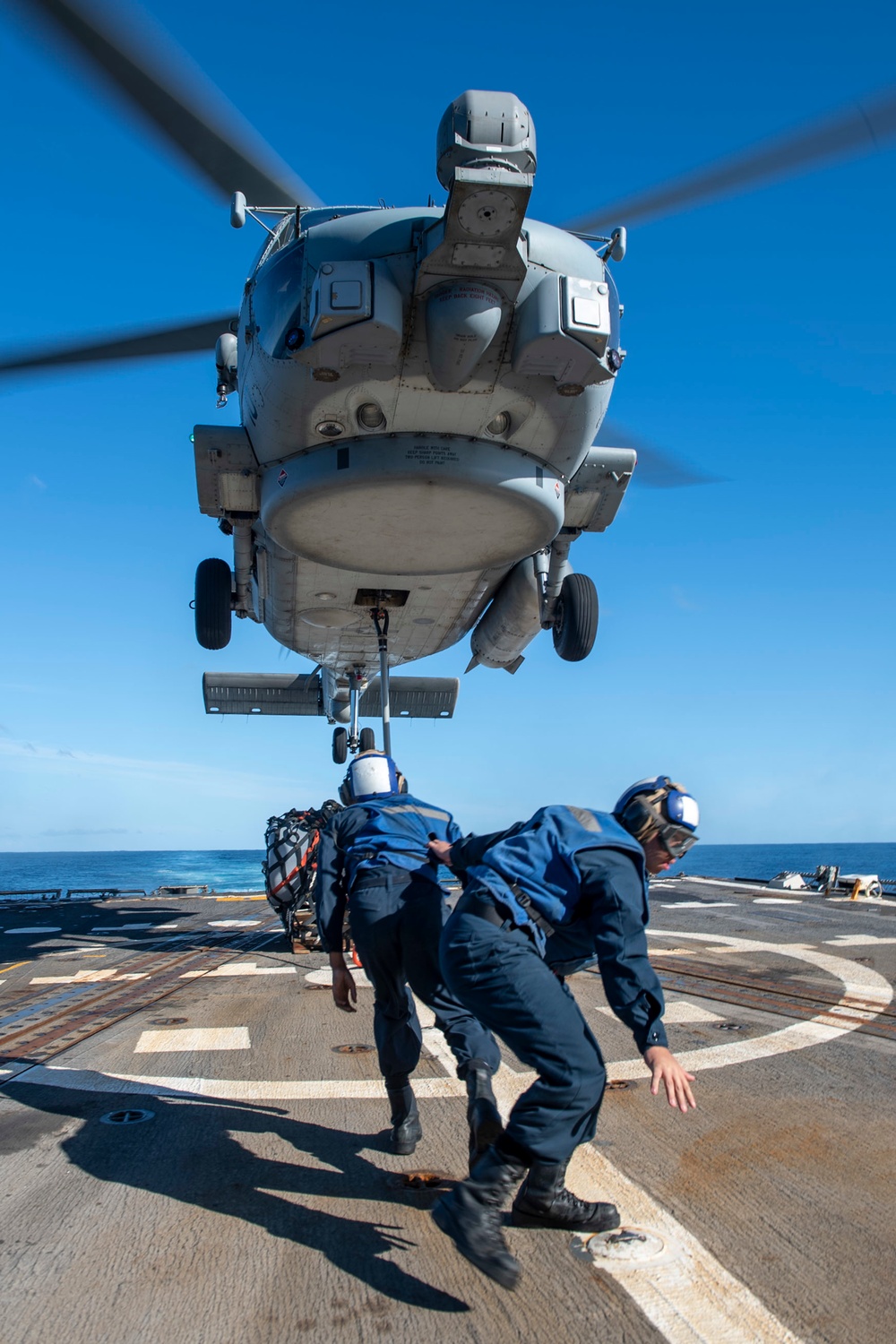 Sailors withdraw from equipment secured to an MH-60R Seahawk