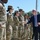 Acting SecAF Roth visits Joint Base Andrews A civilian official in a dark blue suit and tie is greeting a line of military personnel in OCP (Operational Camouflage Pattern) uniforms outdoors. The civilian is shaking hands with a female service member while smiling broadly, suggesting a formal visit or recognition event. The setting appears to be a military installation on a clear, sunny day.