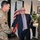 Acting SecAF Roth visits Joint Base Andrews A military officer in OCP (Operational Camouflage Pattern) uniform is shaking hands with a civilian man in a dark pinstripe suit inside what appears to be a military facility or office. A second service member in OCP uniform stands in the background observing the exchange. The setting includes an American flag and a POW/MIA flag, suggesting an official or ceremonial occasion.