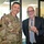 Acting SecAF Roth visits Joint Base Andrews Two individuals pose together indoors, likely at a military installation. A uniformed U.S. Air Force officer stands beside a civilian in a suit, who is holding up a challenge coin. The occasion appears to be a formal recognition or ceremonial exchange.