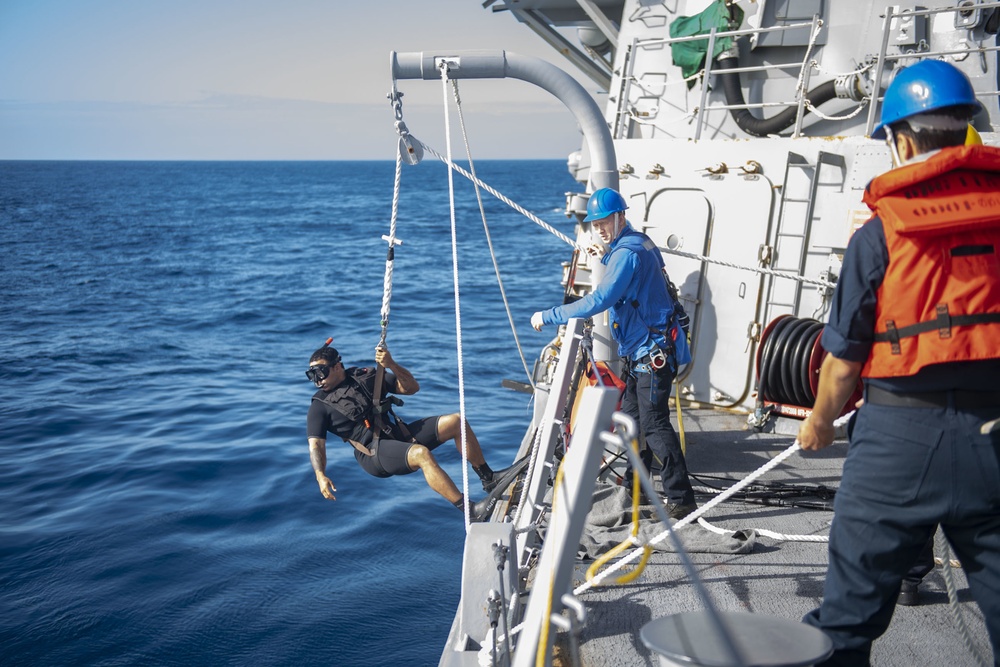 Sailors aboard USS Rafael Peralta (DDG 115) lower Boatswain’s Mate 3rd Class Martin Sadler, from San Louis Obispo, Calif., into the water