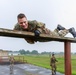 Maj. James Fink climbs over an obstacle