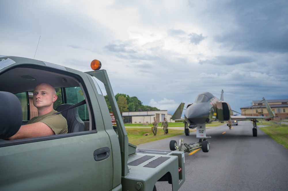 Team JSTARS maintainers tow an F-4C Phantom II to wing HQ for permanent static display