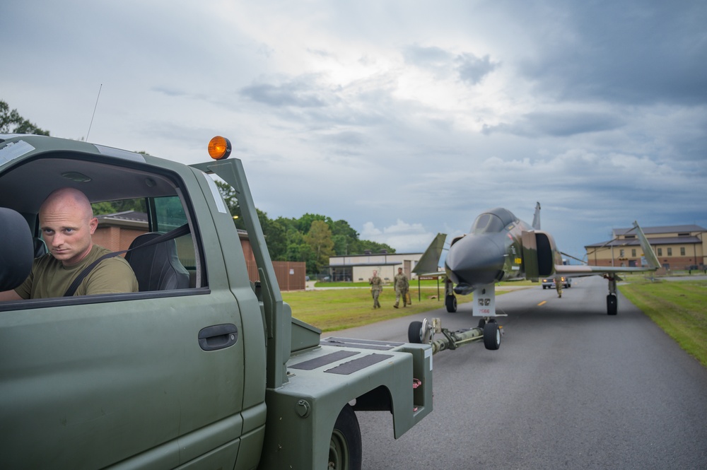 Team JSTARS maintainers tow an F-4C Phantom II to wing HQ for permanent static display