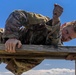 Maj. James Fink climbs over an obstacle