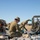 Talisman Sabre 21: U.S., Australian forces perform bilateral fuel training Two military personnel in camouflage uniforms are working with fuel or fluid transfer equipment in an arid outdoor environment. They are kneeling and handling hoses, pipe fittings, and pumping machinery laid out on a tarpaulin. The setting appears to be a field training exercise or forward operating base logistics operation.