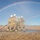 Talisman Sabre 21: U.S., Australian forces perform bilateral fuel training Four firefighters in full protective gear are operating a fire hose together in an open, dry field. A vivid rainbow arcs across the clear blue sky behind them, likely created by the mist from the water spray. The scene appears to be a training exercise given the open terrain and coordinated team positioning.