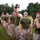 Officer Candidates School Combat Fitness Test A group of U.S. Marine Corps personnel are conducting a physical training exercise outdoors on a grassy field. Several Marines are lifting what appear to be military ammunition cans overhead as part of a fitness drill. The scene takes place during early morning or evening hours based on the ambient lighting.