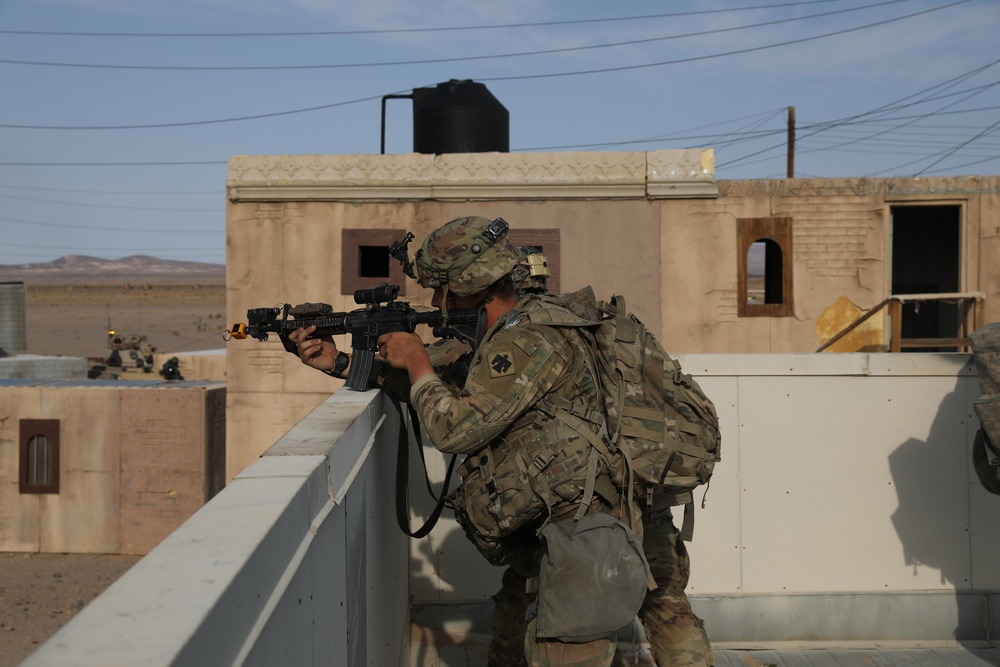 A Soldier of the 45th Infantry Brigade Combat Team fires upon members of the opposing forces from a rooftop