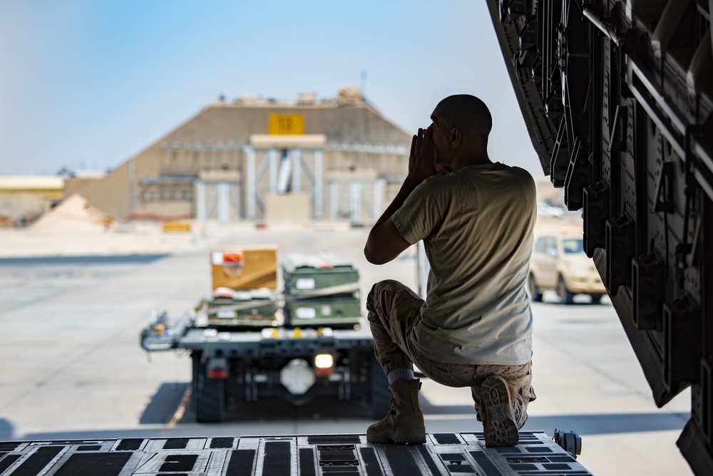 U.S., host nation Air Force members load cargo onto a Kuwait C-17 Globemaster III