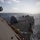 USS Sioux City Transits the Caribbean Sea The image shows the deck of a U.S. Navy guided-missile destroyer underway at sea, photographed from an elevated position on the ship's superstructure. The aft deck is visible, featuring a covered gun mount or weapons system, a helicopter landing pad with markings, and various deck equipment. The vessel is sailing through moderately choppy open ocean under a partly cloudy sky.