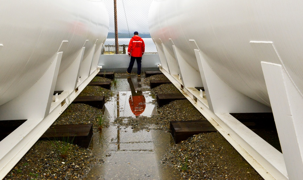 Petty Officer 2nd Class Craig Bennett, a marine science technician with the Coast Guard Marine Safety Task Force (MSTF), inspects a fuel oil storage facility in Teller, Alaska, July 20, 2021. As part of the inspection, MSTF members discuss response plans, review documentation, and inspect equipment and fuel storage facilities to ensure regulatory compliance. U.S. Coast Guard photo by Petty Officer 2nd Class Melissa E. F. McKenzie.