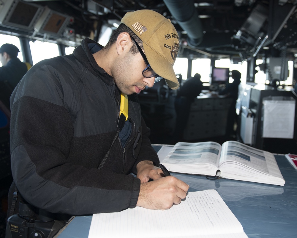 Ensign Jason Brooks, from Cincinnati, Ohio, writes an entry into a log book